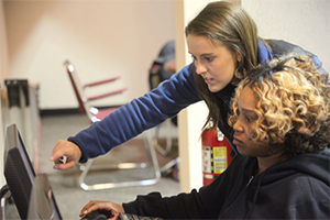 Women helping another woman use a computer